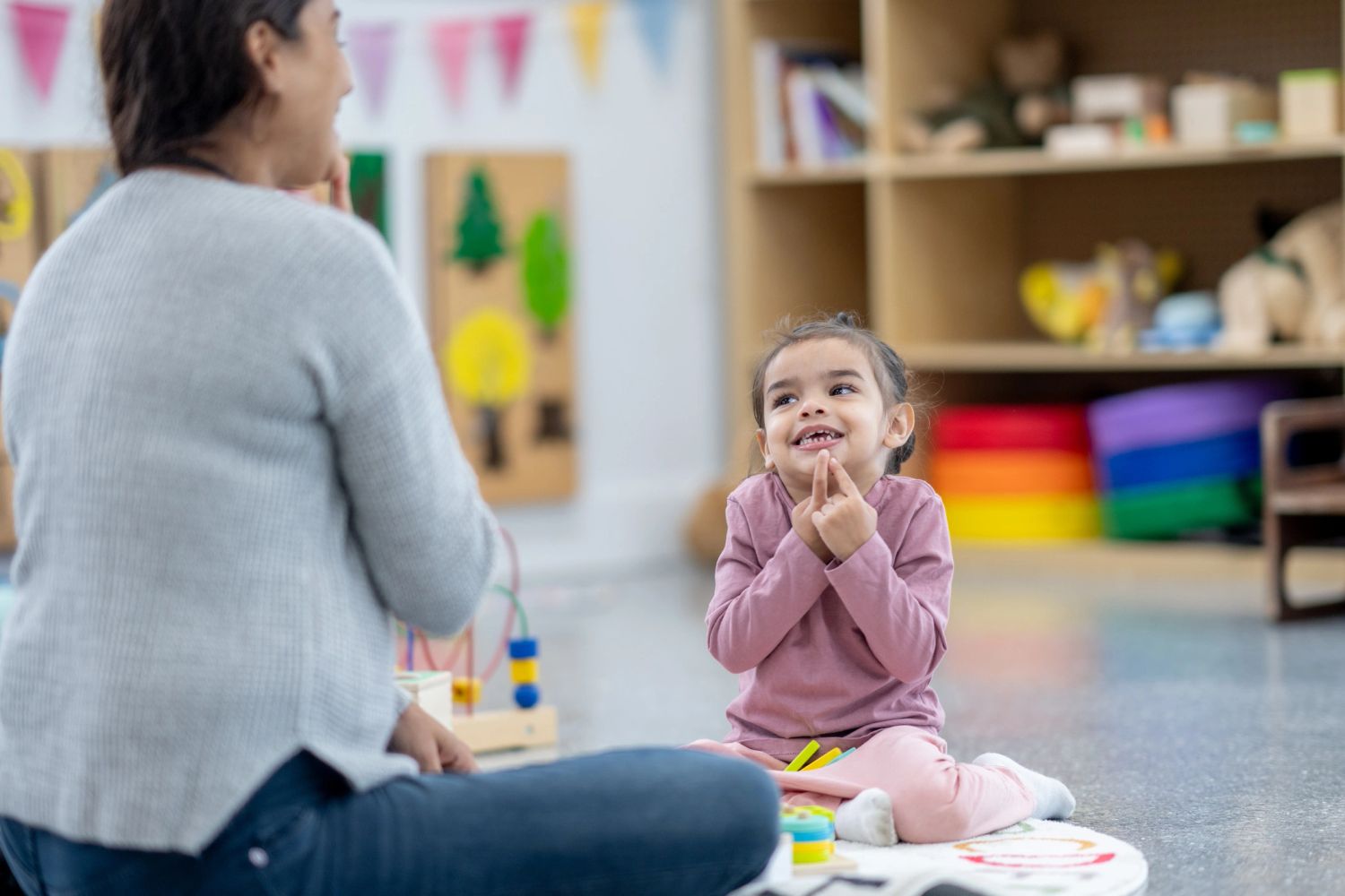 Young girl happily playing and communicating with a speech pathologist in a colourful therapy room.