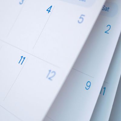 Close-up of a calendar showing dates in blue on white pages.