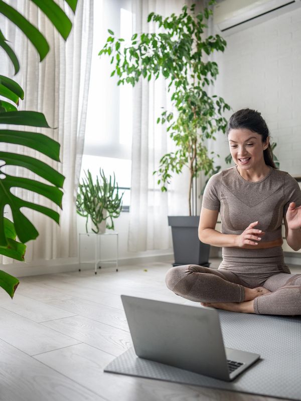 Young woman doing yoga while interacting with laptop.