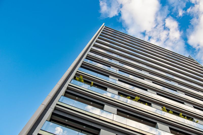 Low angle view of the exterior facade of a modern building with plants in one of the balconies