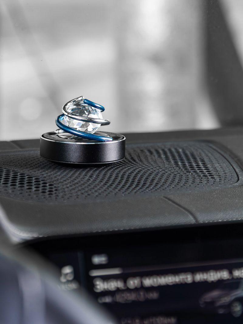 Close up of air freshener with crystal ball and spinner on car dashboard vent