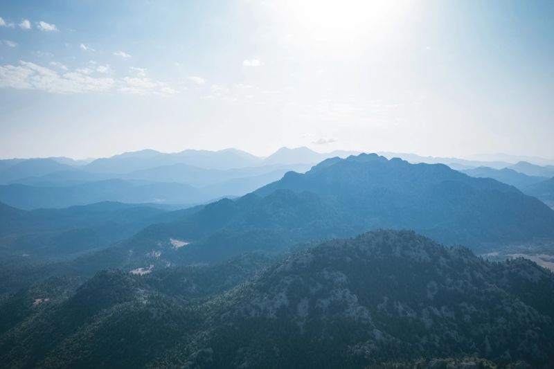 Magnificent nature with mountains and forests. Beautiful sunny valley with blue sky in summer. Aerial view with drone.