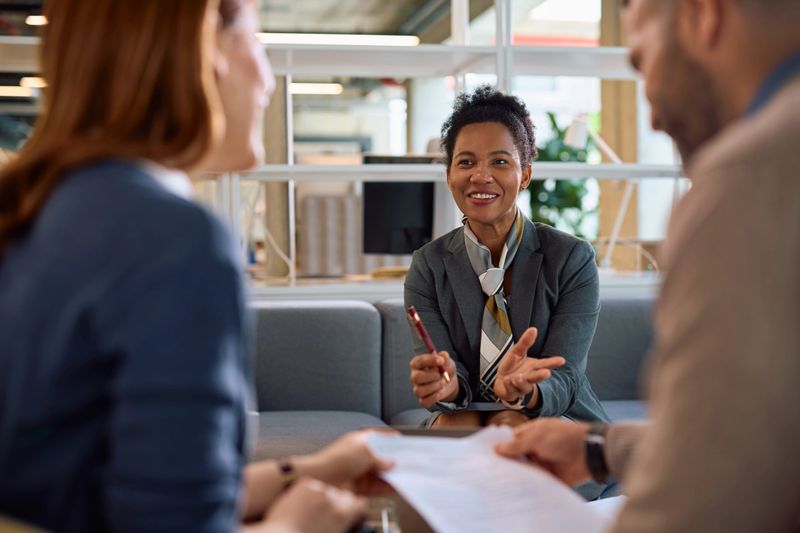 Happy African American bank manager communicating with her clients of a meeting in the office.
