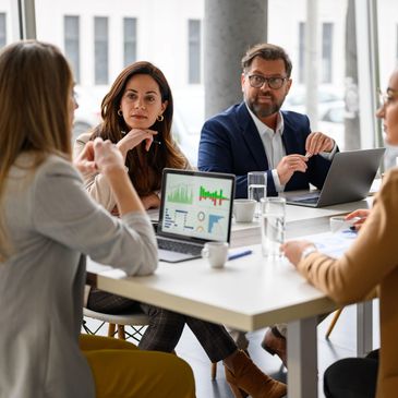 Four professionals engaged in a business meeting around a table with laptops and charts.