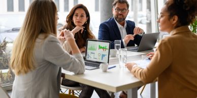 Four professionals discussing data in a meeting.