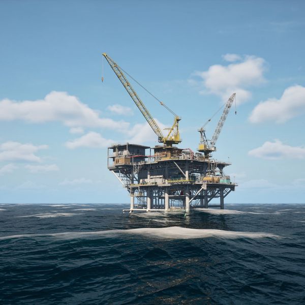 Offshore oil rig with cranes in the middle of the ocean under a clear sky.