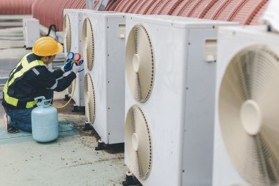 Technician repairing an HVAC system on a rooftop.