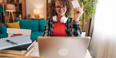 Young woman using a laptop and holding a credit card at home.