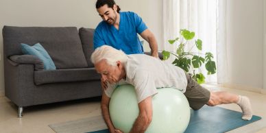 Senior man exercising with therapist using an exercise ball.