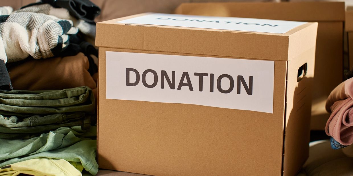 Cardboard box labeled 'Donation' with folded clothes around it.