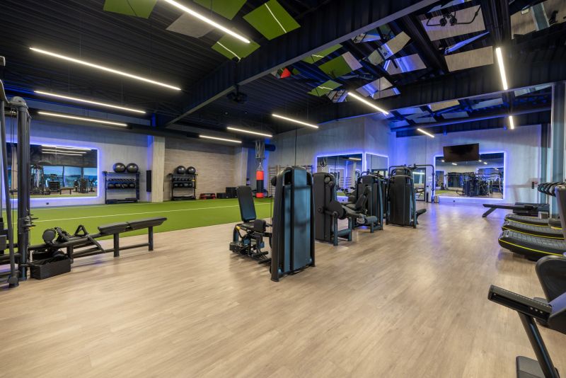 Bright and spacious gym interior featuring modern equipment, mirrors, fitness machines, and neon lighting, designed to promote a motivating and enjoyable workout atmosphere for fitness enthusiasts