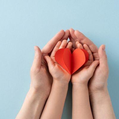 Hands holding a paper heart symbolizing care and love.