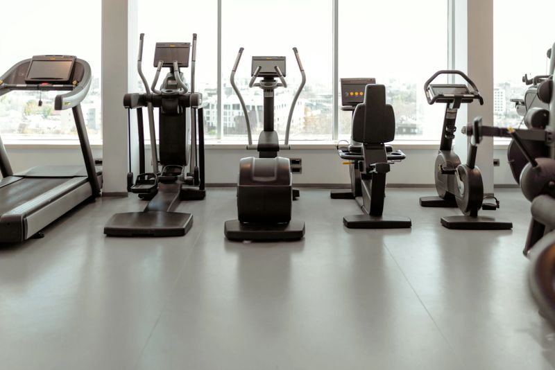 Row of state-of-the-art cardio machines including treadmills and exercise bikes in a clean, spacious fitness center. Health and wellness background.