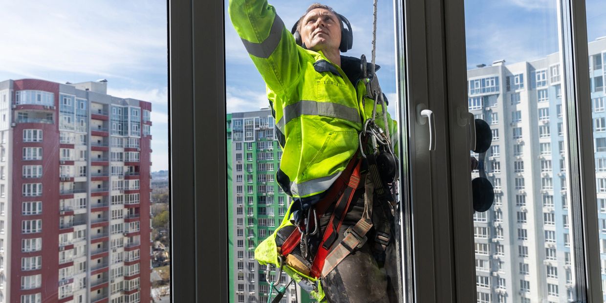 Window cleaner in safety gear working on a high-rise building.
