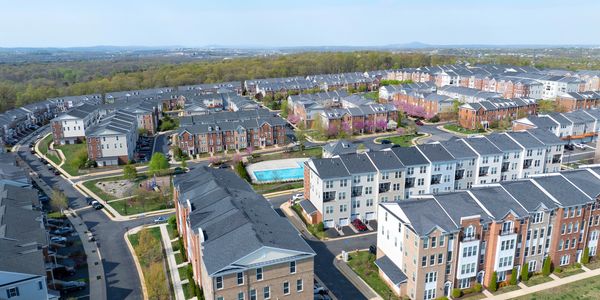 Aerial view of a suburban neighborhood with townhouses and a swimming pool.