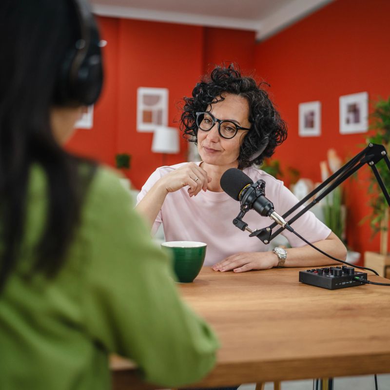 woman in the podcast studio talk and record, focus on a caucasian curly hair woman talk into a mic