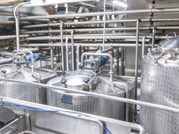 Industrial stainless steel tanks and pipes in a factory setup.