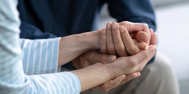 Two people holding hands in comfort.