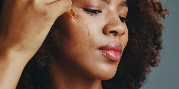 Woman applying facial serum with dropper.