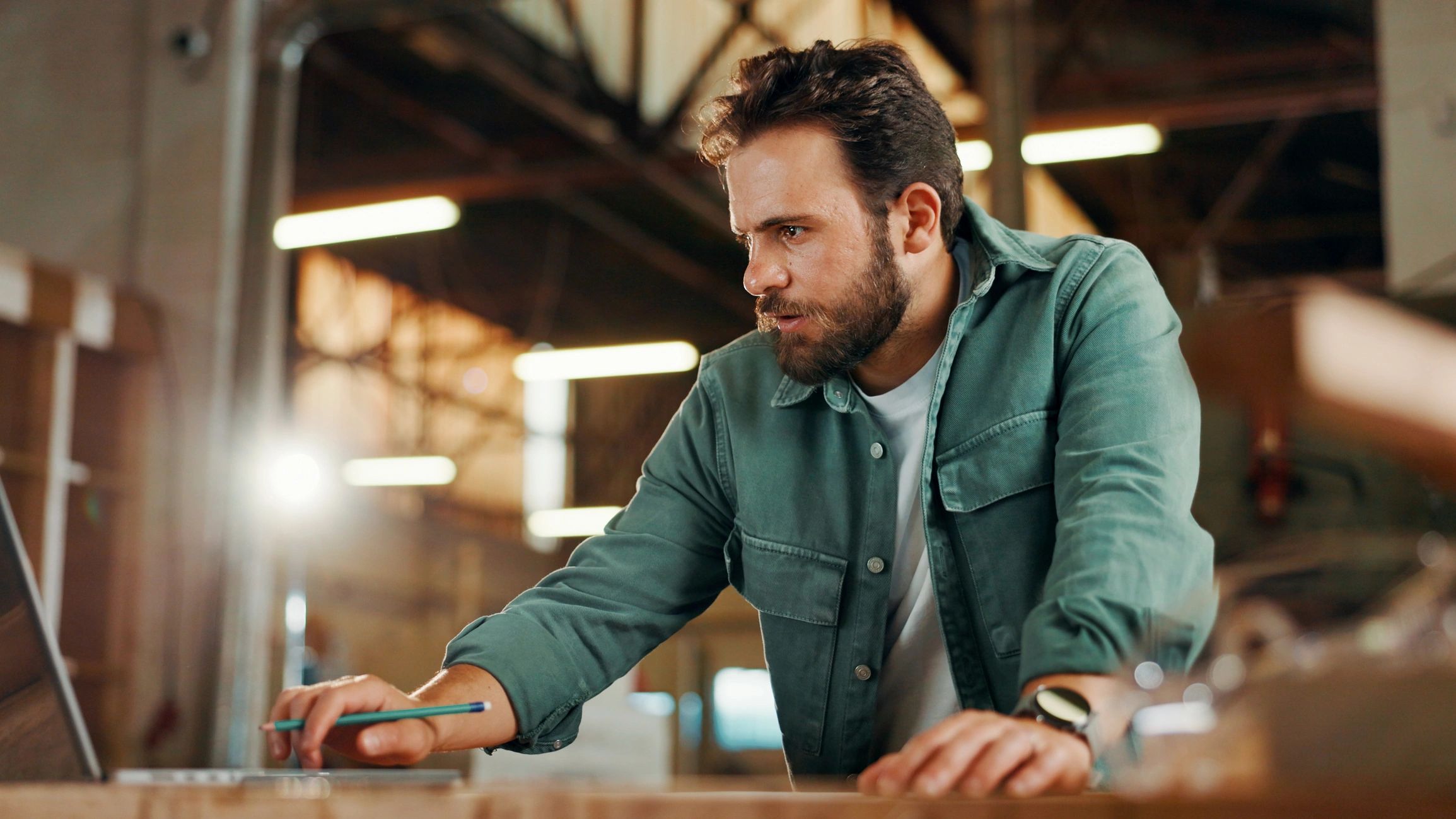 Man working intently on a laptop in an industrial setting.