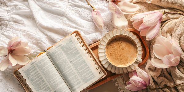 Open book, coffee, and flowers on a cozy background.