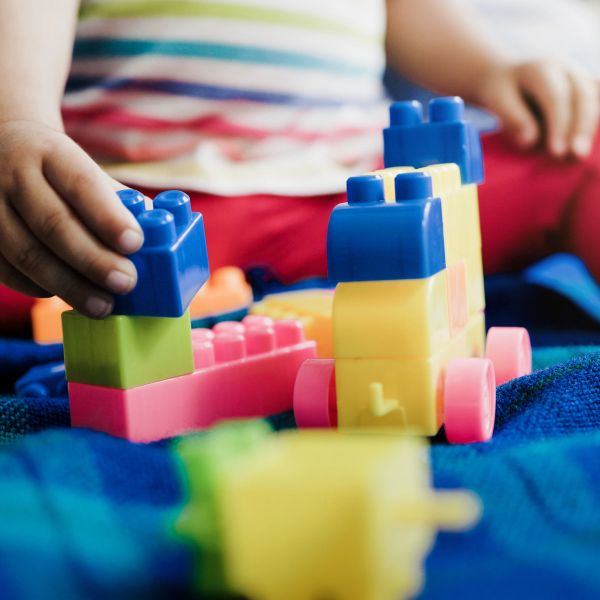 A child plays with colorful building blocks on a blue surface.