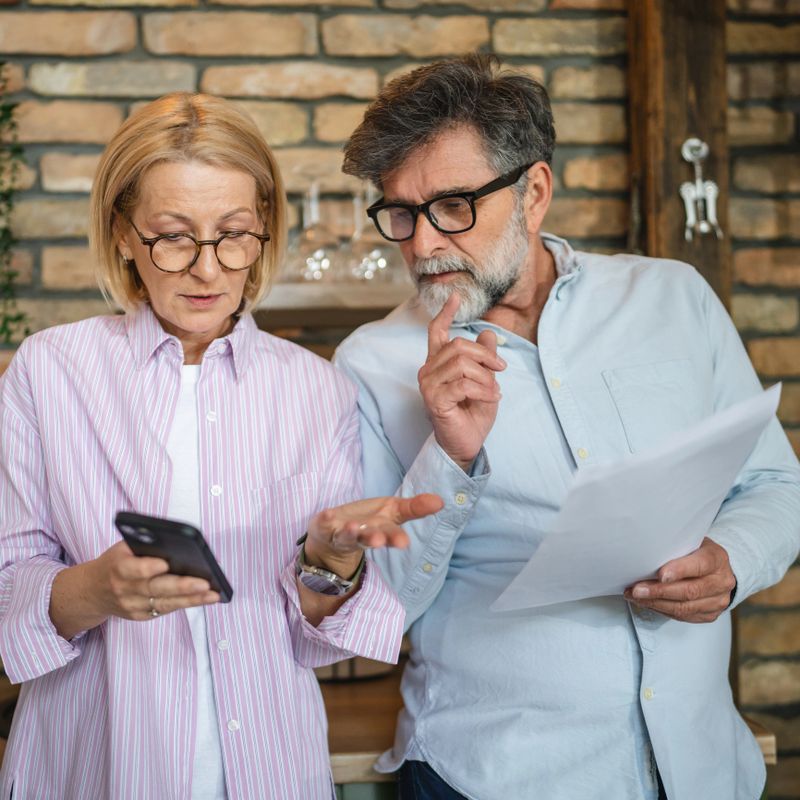 mature couple review, analysis document and use mobile at kitchen