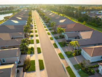 Aerial view of a suburban street with houses and palm trees.