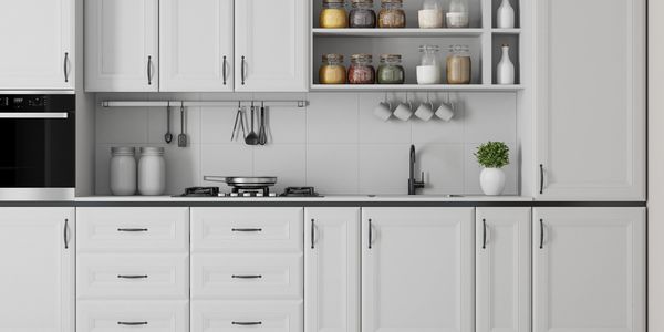 Modern all-white kitchen with black countertop and organized shelves.