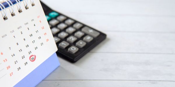 Desk calendar with the 30th circled, next to a calculator.