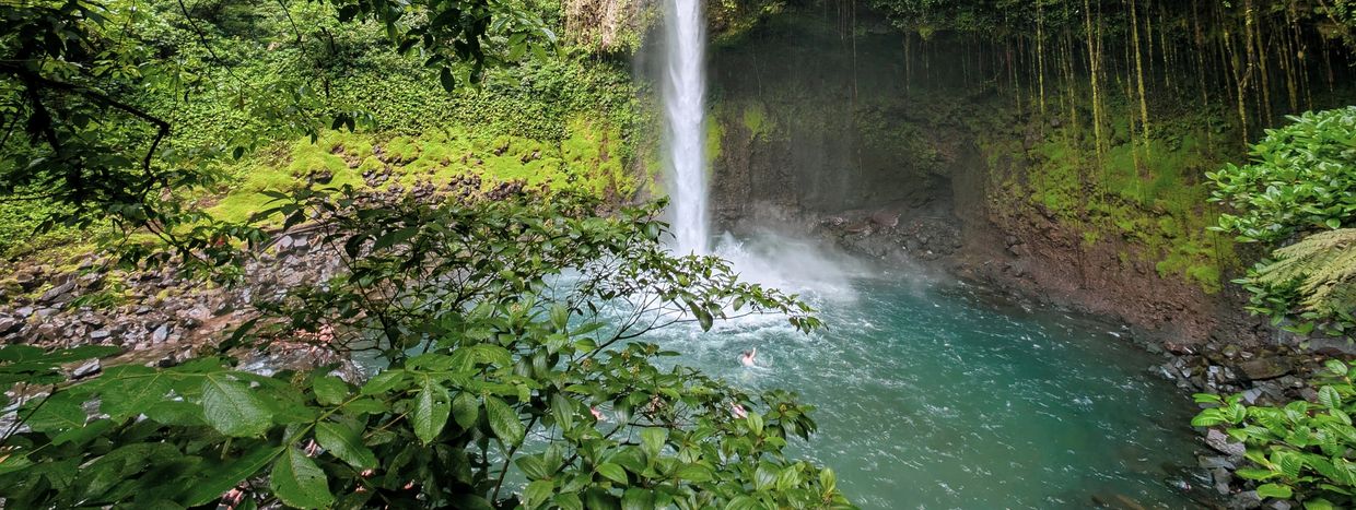 Pareja de Viajeros tomando un baño frente a una catarata en Costa Rica