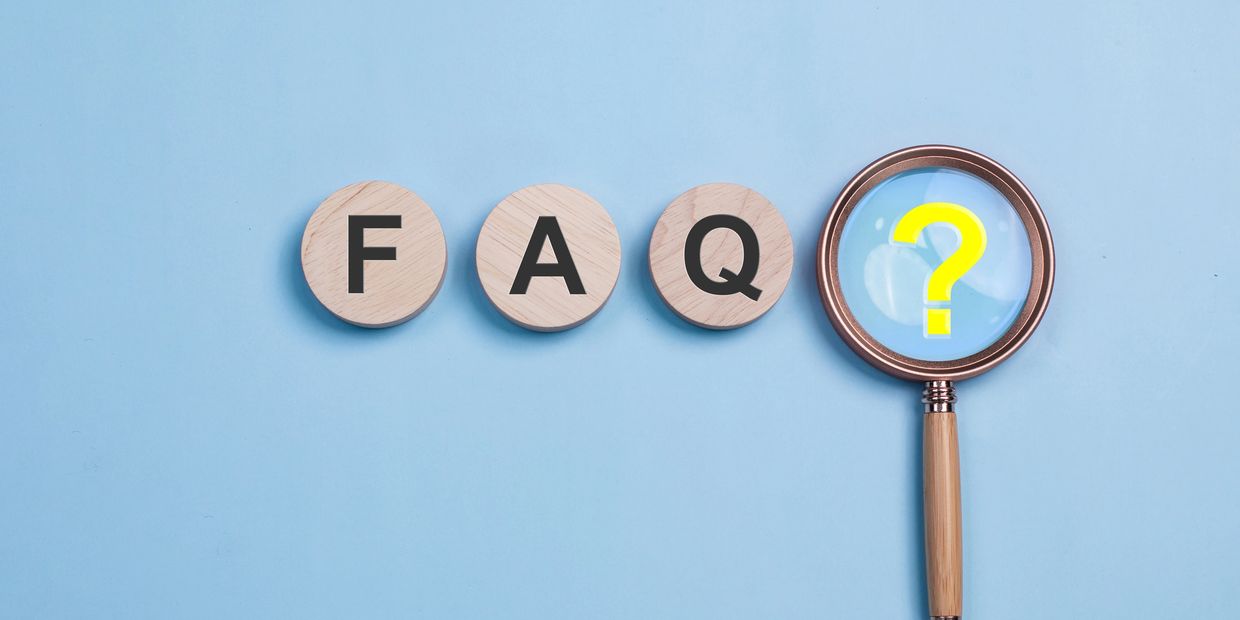 Wooden blocks spelling FAQ with a magnifying glass highlighting a yellow question mark.