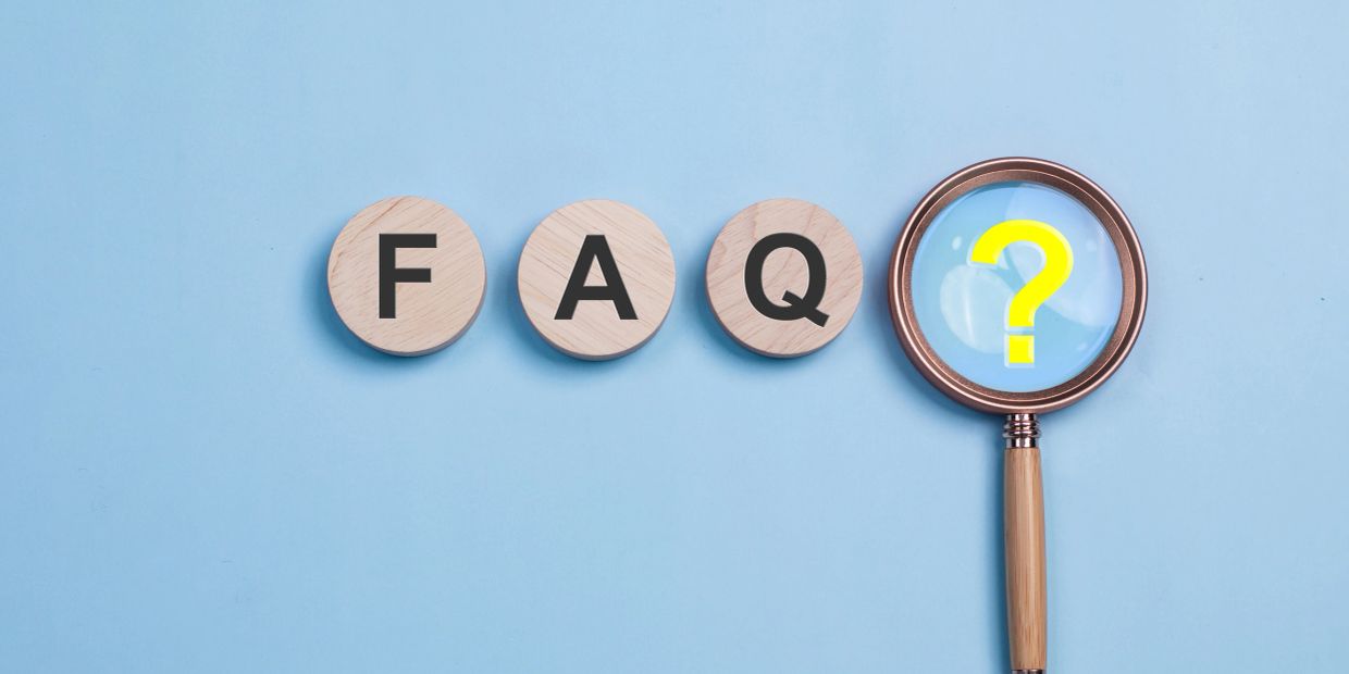 Wooden blocks spelling FAQ with a magnifying glass and question mark.
