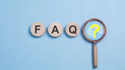 FAQ concept with question mark under magnifying glass.