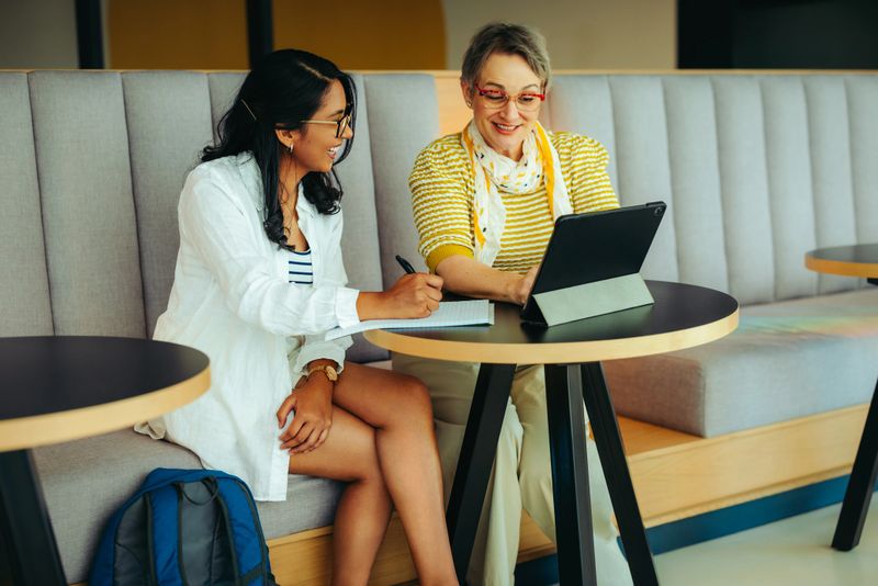 A tutor and student study together, utilizing digital technology in a contemporary setting. This image highlights education, mentorship, and the collaborative learning experience.