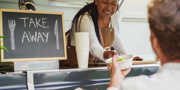 Woman serving takeaway food to a customer.