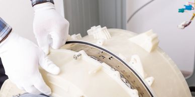 Hands in white gloves assembling a washing machine part.