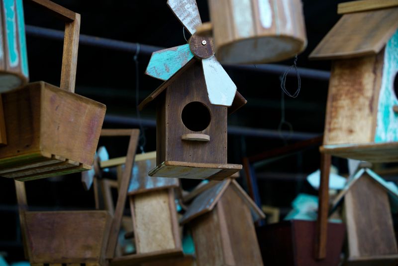 A collection of vintage wooden birdhouses creatively displayed in a rustic market setting. This charming and artistic arrangement showcases craftsmanship and nature's beauty.