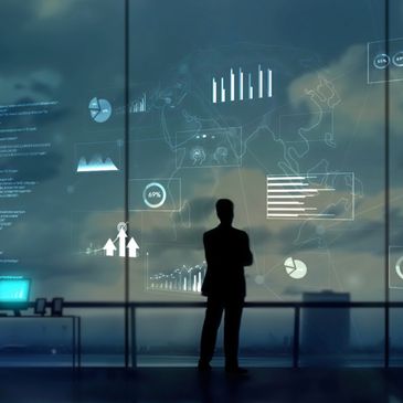 Silhouette of a person analyzing futuristic data charts on a large transparent screen.
