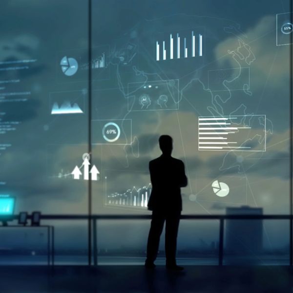 Silhouette of a person analyzing digital data charts on a large screen.
