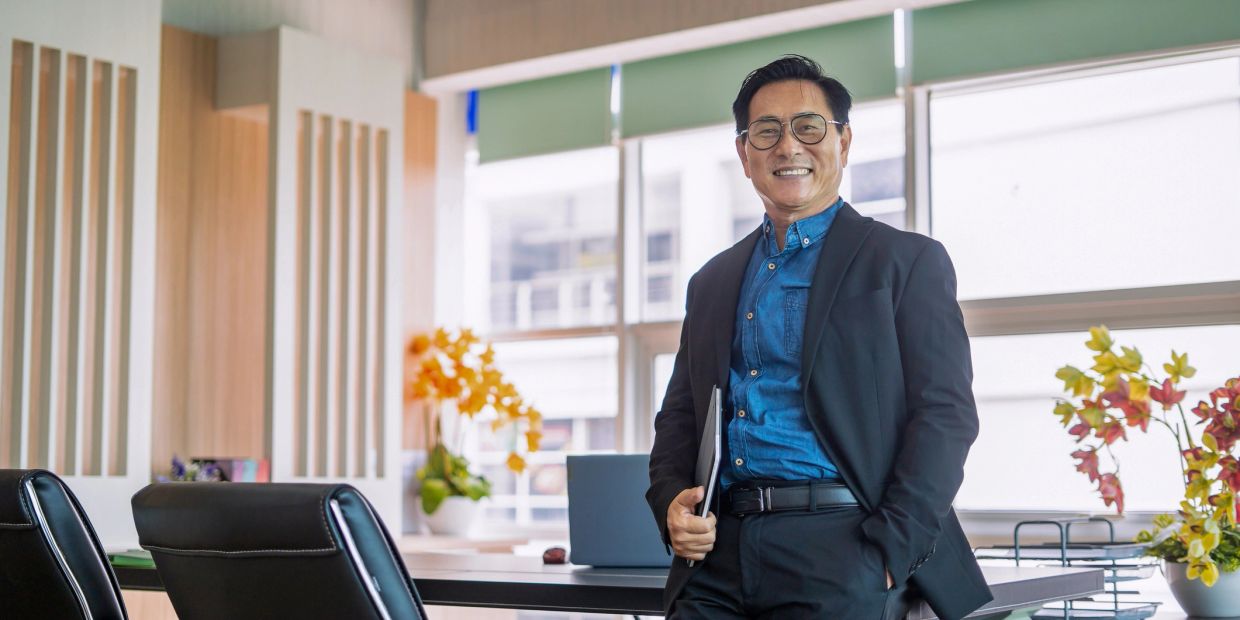 Smiling businessman in office holding a laptop.