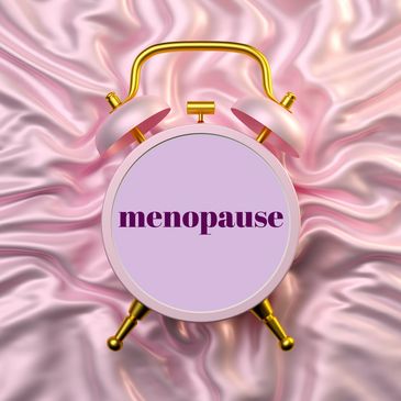 Alarm clock with 'menopause' text on a pink satin background.