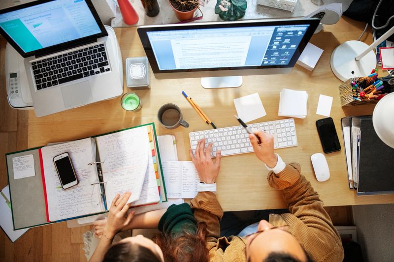 Male and female student collaborate at a well-used desk