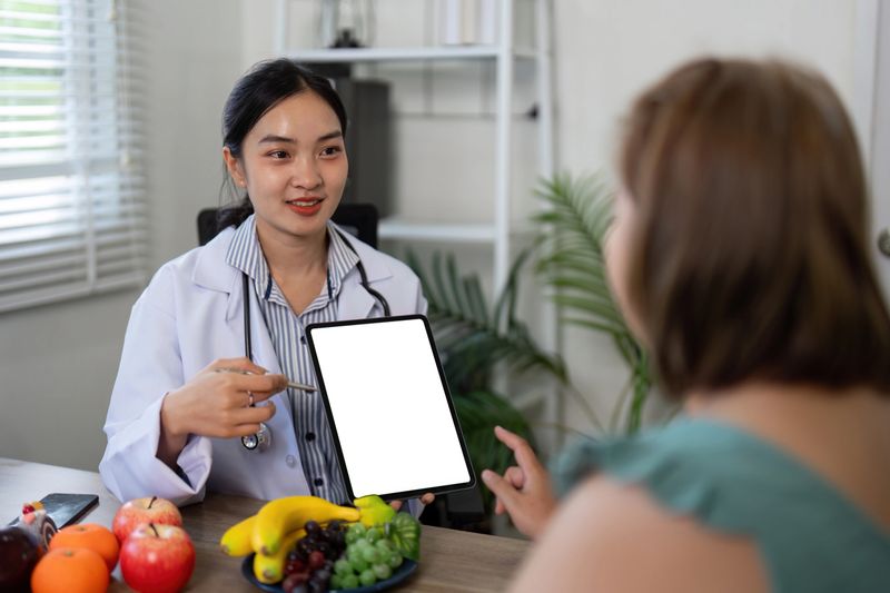 A nutritionist discusses dietary choices with a client, showcasing vibrant fruits and vegetables to promote healthy eating habits. The focus is on personalized dietary advice.