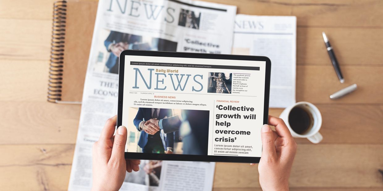 Person holding a tablet displaying a news article about economic growth.