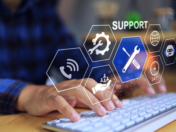 Hands typing on keyboard with digital support service icons overlay.