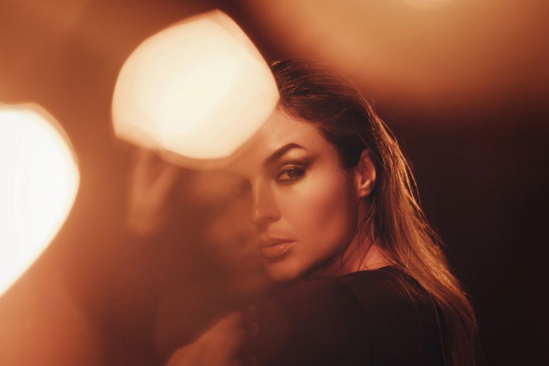 Portrait of beautiful woman captured with moody lighting, lens flares and bokeh.