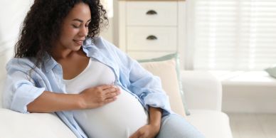 Pregnant woman smiling and holding her belly.