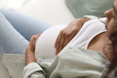Pregnant woman gently touching her belly.