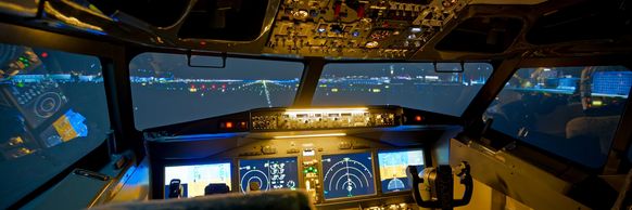Nighttime view from an airplane cockpit on a runway.